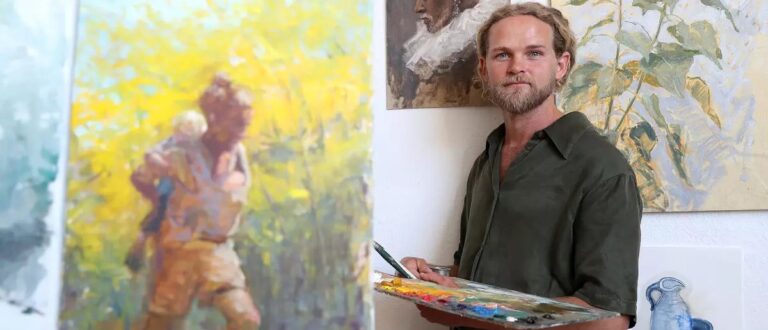 Chapman Hamborg, with his self-portrait at left, at the Hamborg Academy of Art studio in Huntington Beach. (Don Leach / Staff Photographer)