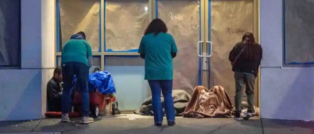 Volunteers Jorge Solorzano, left, a Health Coach at CalOptima; Yolie Negrete, center, a program supervisor at City Net, and Katherine Ibarra, right, of the Garden Grove Regional Center, speak with homeless individuals in the entrance to a building on W. Civic Center Drive in downtown Santa Ana early Tuesday morning, Jan. 23, 2024. Volunteers for the Everyone Counts, Point In Time, a homeless survey, spread out throughout central Orange County on Tuesday, the first day of the survey, to gather data that will help address homeless issues. (Photo by Mark Rightmire, Orange County Register/SCNG)